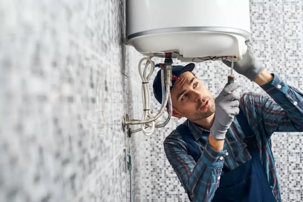Worker set up electric heating boiler at home. Close-up of young handyman